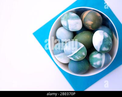 Blue, green, turquoise and white homemade easter eggs colored with a red cabbage natural colour on a white background with blank space decorated. Stock Photo