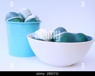 Blue, green, turquoise and white homemade easter eggs colored with a red cabbage natural colour on a white background with blank space decorated. Stock Photo