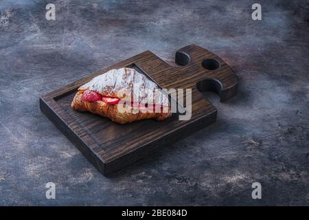 Delicious croissant with strawberry on wooden board for breakfast Stock Photo