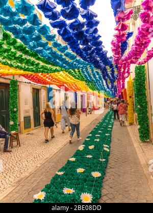 People walking down a highly decorated street in Tomar during the traditional Festa dos Tabuleiros (Festival of the Trays). Portugal Stock Photo