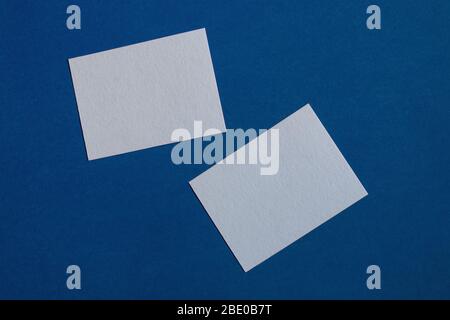 two white sticky notes on blue wall Stock Photo