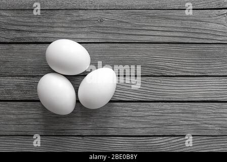 three white eggs on gray wooden background Stock Photo