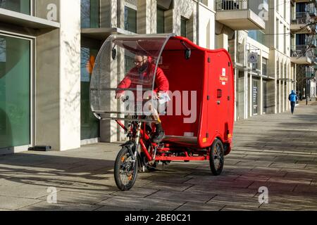 Cycling Royal Mail postman on electric cargo bike, e-Trike, powered by a combination of solar, battery, pedal and brake technology Stratford London UK Stock Photo