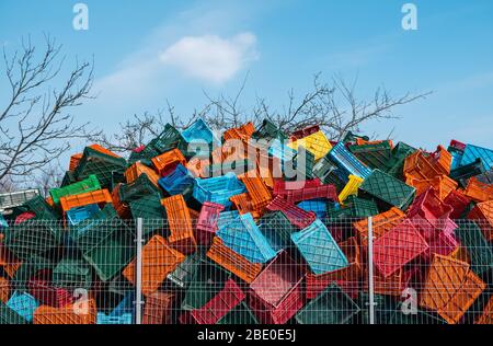 Old plastic boxes in a warehouse as a trash behind the metal mesh fence. Stock Photo