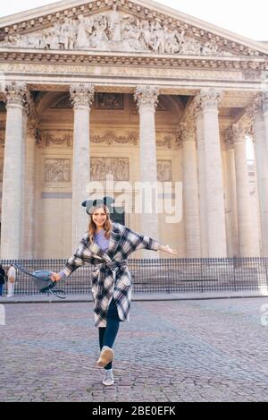 a young woman wearing a mikimaus hat and carrying a backpack walks on the square in front of the Pantheon, Paris, France Stock Photo
