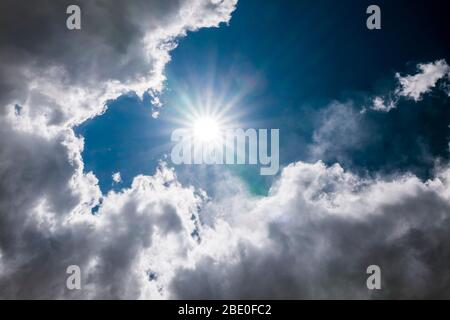 Unusual cloud formations & sunburst against clear cobalt blue sky; central Colorado; USA Stock Photo