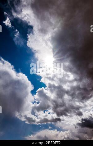 Unusual cloud formations & sunburst against clear cobalt blue sky; central Colorado; USA Stock Photo