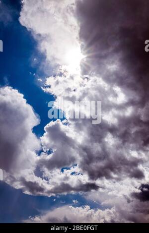 Unusual cloud formations & sunburst against clear cobalt blue sky; central Colorado; USA Stock Photo