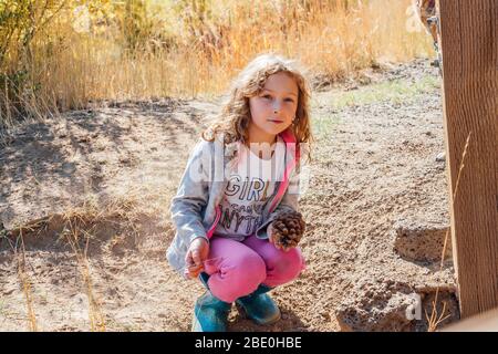Girl playing outside in fall holding pine cone Stock Photo