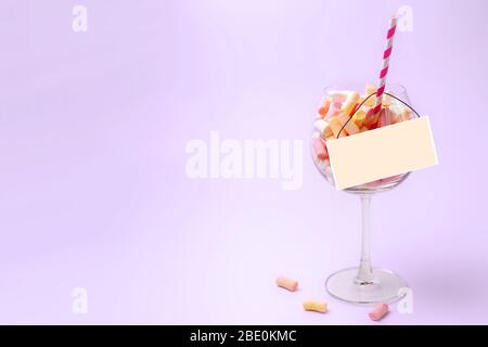 White plate on a glass with mini marshmallows on a light raspberry background. Multi-colored marshmallows in a glass. Confectionery concept. Copy space close-up Stock Photo