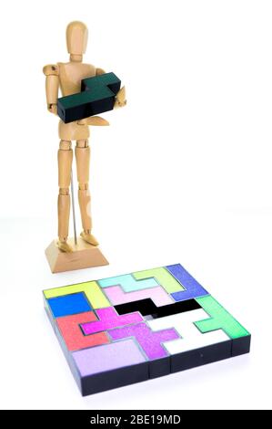 Small wooden mannequin holding the one piece needed to solve the puzzle, isolated on a white background Stock Photo