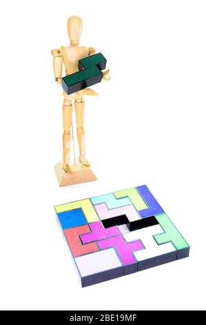 Small wooden mannequin holding the one piece needed to solve the puzzle, isolated on a white background Stock Photo