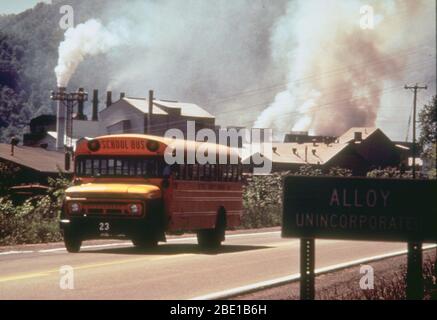ca. 1998-1999 - school bus driving down road in front of polluting factory (possibly Alloy, West Virginia) Stock Photo