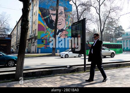 Street scene in Almaty, man walking and looking to a self phone, Kazakhstan Stock Photo