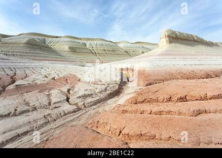Young boy in yellow jacket hiking on bizarre chalky mountains, colorful rock formations of Boszhira in Western Kazakhstancliff Stock Photo