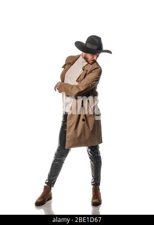 Attractive young male model posing in leather pants and long coat isolated on white backgorund Stock Photo