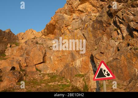 Hazard rockfall sign with stone cliff in background. Jersey, Channel Islands. Stock Photo