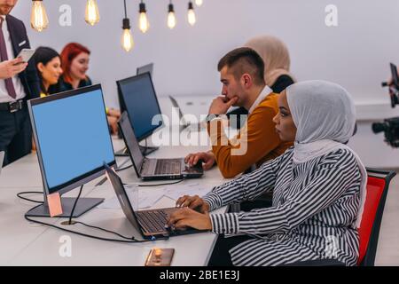 Multi-ethnic coworkers sitting at desks and working on computers in a modern office room Stock Photo
