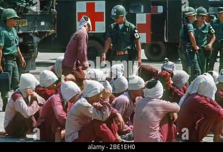 Viet Cong POWs sit on the ramp at Tan Son Nhut Air Base under the watchful eyes of South Vietnamese military police.  The POWs will be airlifted to Loc Ninh, South Vietnam for the prisoner exchange between the United States/South Vietnam and North Vietnam/Viet Cong militaries. Stock Photo