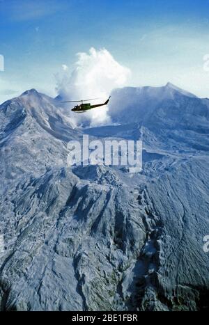 Left side view of a UH-IN Iroquois helicopter from the 304th Aerospace Rescue and Recovery Squadron in flight near the steam rising from the crater several days after a large eruption. Stock Photo