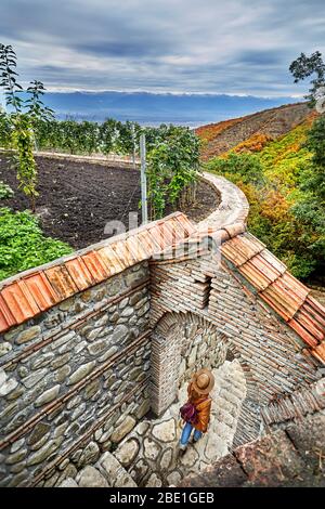 Tourist woman in Hat with backpack on the stairs of Bodbe monastery in Signagi town, Georgia Stock Photo