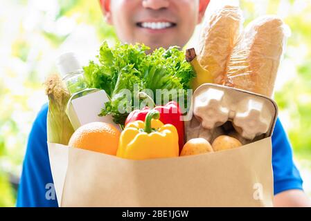 Smiling delivery man holding a grocery bag ready to deliver to the customer at home Stock Photo