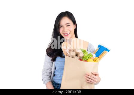 Beautiful smiling Asian woman holding paper shopping bag full of food and groceries isolated on white background Stock Photo