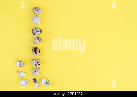 Many small easter eggs on the yellow background. Place for text. Flat lay. Stock Photo