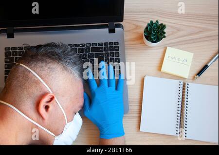 Doctor researcher asleep on desk, on laptop. Male hands in blue protective gloves. Tired overworked in clinic. Keep fighting in medical and health con Stock Photo