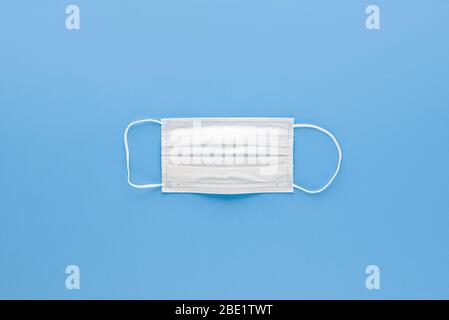 New clean white medical face mask isolated on light blue background top view Stock Photo