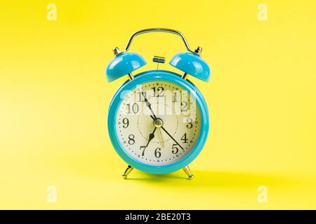 Blue alarm clock on yellow background. Front views Stock Photo