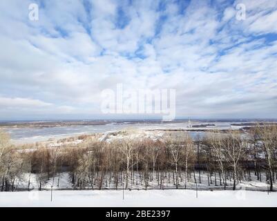 Beautiful early spring river landscape. White clouds over the river and trees on on a sunny day after melting snow. Stock Photo