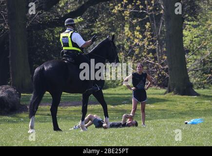 A mounted police officer offers advice to people using Victoria Park, in east London, after it was reopened with reduced opening hours and new control measures in place during the coronavirus outbreak. Stock Photo