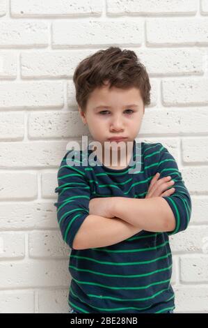 Angry frowning boy on brick wall background. Stock Photo