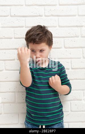 An angry frowning boy threatens with his fist Stock Photo