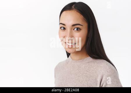Close-up shot ordinary cute young asian millennial girl in winter sweater, look enthusiastic and amused camera, smiling casually, having chat with Stock Photo