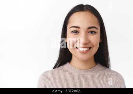 Close-up shot asian woman face with no pimples, acne, natural make-up, smiling joyful, feeling happy and upbeat, having lucky day, enjoy spend Stock Photo