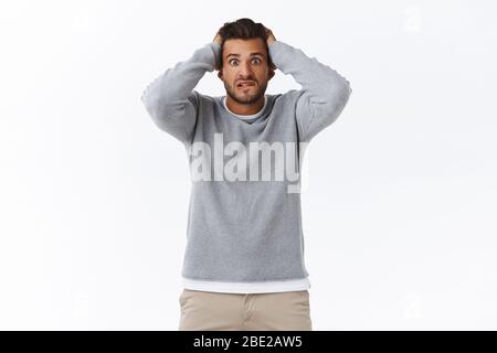 Worried handsome, troubled hispanic bearded guy caught cheeting, looking anxious and troubled, facing tough unsolved problem, grab head, biting lip Stock Photo