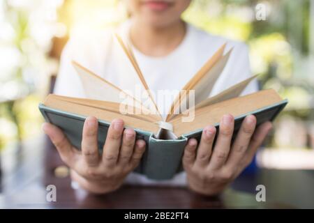 holding book opened in two hands on table, wisdom and knowledge concept Stock Photo