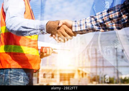 Architect contractor shaking hands with client at construction site Stock Photo