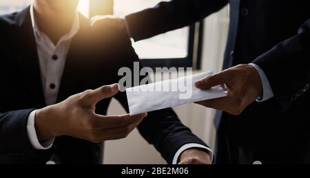 Close up hand of manager giving money bonus in paper envelope to happy office worker,congratulating employee with increasing of salary or promotion as Stock Photo
