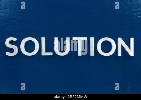 the word solution laid with white metal letters over flat blue surface on flat lay perspective with directly above view in center of picture Stock Photo