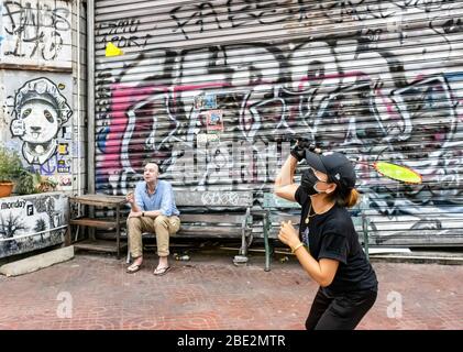 Bangkok, Thailand - February 27th, 2020: A young woman wearing a protective face mask, playing badminton on a street in Bangkok, Thailand. Stock Photo