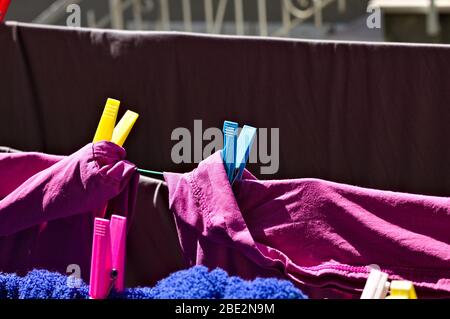 Colored towels and bed sheets hanging on a drying rack with colored clothespins (Pesaro, Italy, Europe) Stock Photo