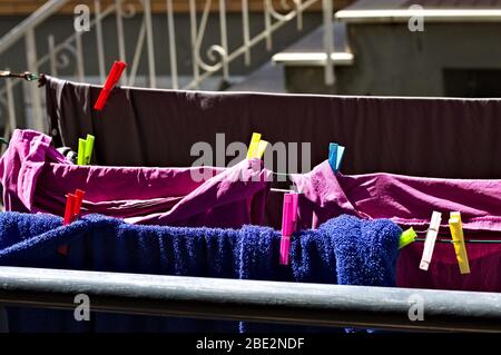 Colored towels and bed sheets hanging on a drying rack with colored clothespins (Pesaro, Italy, Europe) Stock Photo