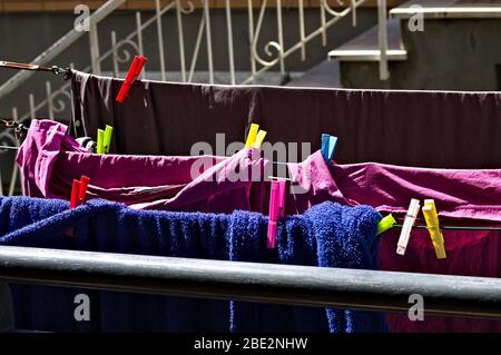 Colored towels and bed sheets hanging on a drying rack with colored clothespins (Pesaro, Italy, Europe) Stock Photo