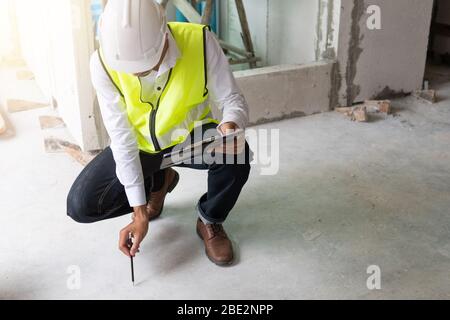 construction inspector sitting and checking cement floor in building Stock Photo
