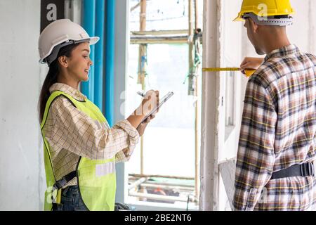 inspector checking and measure by measuring tape with assistant in construction site Stock Photo