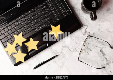 Yellow paper stars over the laptop with place for text. Feedback, Customer Experience Concept Stock Photo