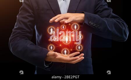 Mens hands hold ball with silhouette of people Stock Photo